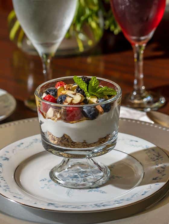 Close up view of fruit and granola parfait sitting on white plate