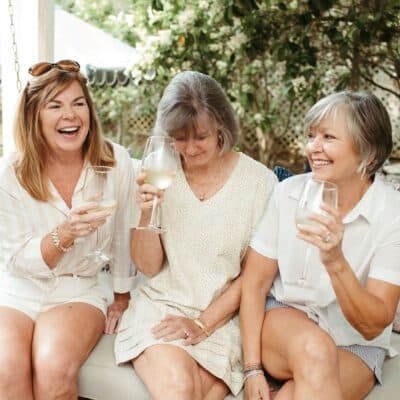 3 women sitting on a swing drinking white wine